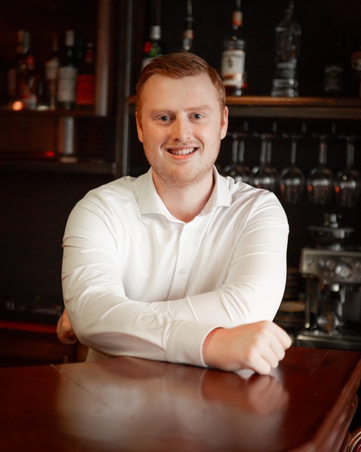 Mensen zitten in een moderne, luxe vergaderruimte met leren banken en inspirerende posters, perfect voor zakelijke vergaderingen of bijeenkomsten te huur.